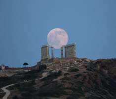 La luna llena se eleva detrás de un árbol al lado del mármol antiguo templo de Poseidón en el cabo Sunion, al sureste de Atenas.  / Foto: AP