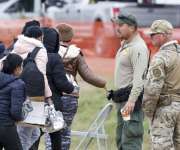 Un grupo de migrantes (i) que pasa junto a agentes de la Patrulla Fronteriza (c) y de la Guardia Nacional de Texas (d), en Shelby Park en Eagle Pass, Texas (EE.UU.). EFE / Archivo