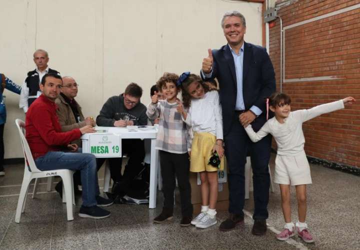 El candidato presidencial colombiano, Iván Duque, saluda tras votar acompañado de sus hijos en un colegio electoral en Bogotá (Colombia). EFE