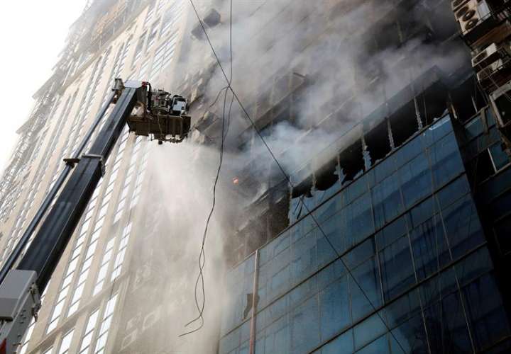 Miembros del cuerpo de bomberos de Bangladesh intentan apagar el incendio que se ha producido en un edificio, este jueves en Dacca (Bangladesh). EFE