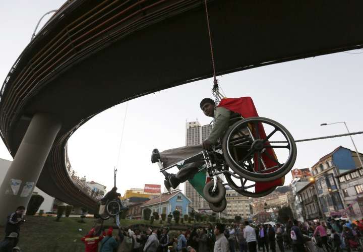 Discapacitados protestan colgando sus sillas de ruedas en un puente