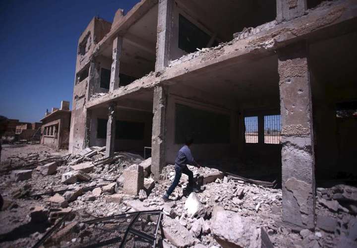 Un niño inspecciona un colegio en ruinas tras unos bombardeos en el pueblo de Deir al Asafi, al sureste de Damasco (Siria).  /  Foto: EFE Archivo