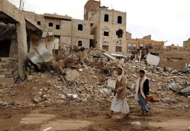 Dos hombres pasan por delante de las ruinas de un edificio destruido por un bombardeo de la coalición árabe liderada por Arabia Saudí en Saná, Yemen.  /  Foto: EFE Archivo
