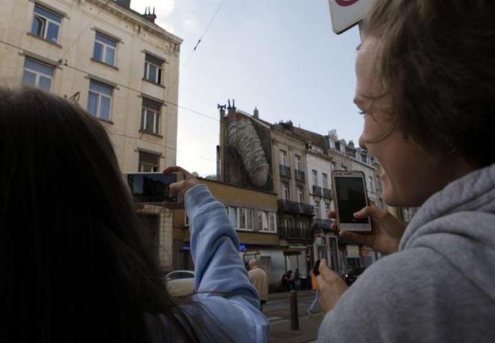 Dos personas fotografían uno de los grafitis de alto contenido sexual que han aparecido esta semana en Bruselas.  /  Foto: EFE