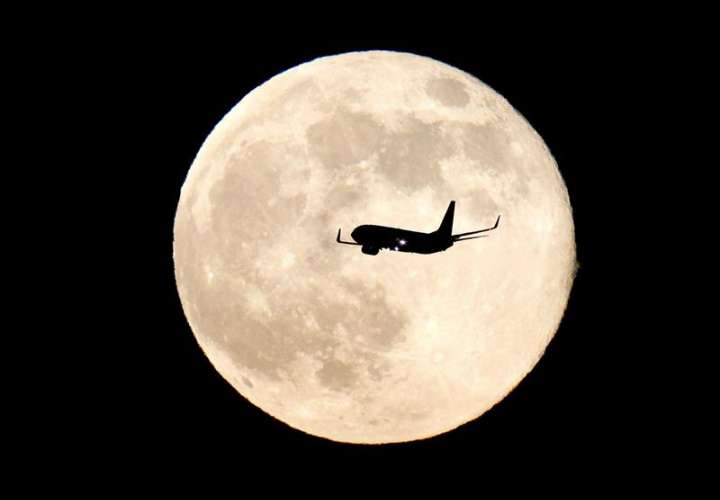 Un avión sobrevuela el cielo con la Luna de fondo. EFE/Archivo