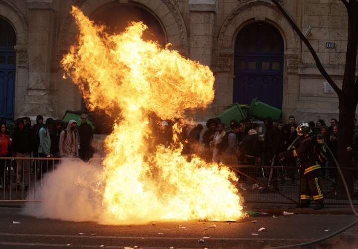 Los bomberos franceses intentan extinguir las papeleras quemadas mientras los estudiantes se reúnen durante una manifestación contra la brutalidad policial, tras la supuesta violación de Theo, fuera de la escuela secundaria 