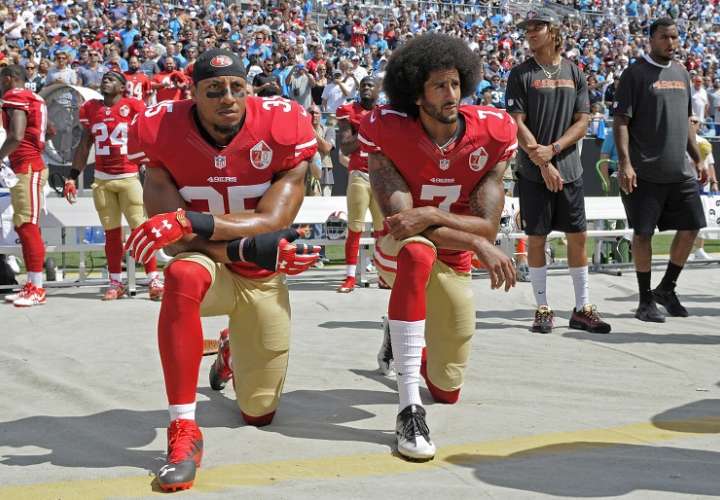 Colin Kaepernick (derecha) junto a Eric Reid (35) se arrodillan mientras se entona el himno de Estados Unidos. Foto AP 