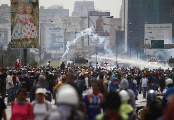 Fuerzas de seguridad pulverizan a los manifestantes con cañones de agua durante una protesta contra el gobierno exigiendo al presidente venezolano, Nicolás Maduro, abrir un llamado corredor humanitario para entrega de medicamentos y ayuda alimentaria. AP