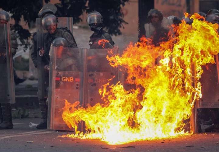 Miembros de la Guardia Nacional Bolivariana (GNB) se protegen del fuego en medio de unos enfrentamientos con manifestantes durante una de las protestas en el marco de la huelga general de dos días convocada por la oposición en Caracas (Venezuela). EFE