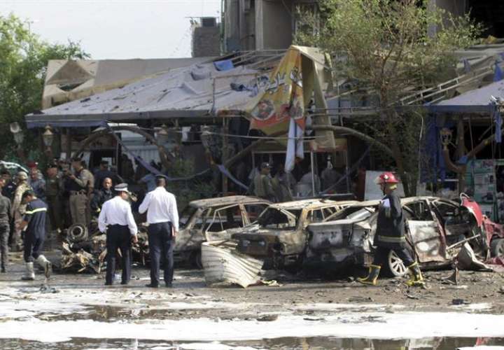 Agentes de policía y bomberos iraquíes inspeccionan la zona de la explosión de un coche bomba en Bagdad, cerca de un restaurante, registrada en 2014. EFE/Archivo