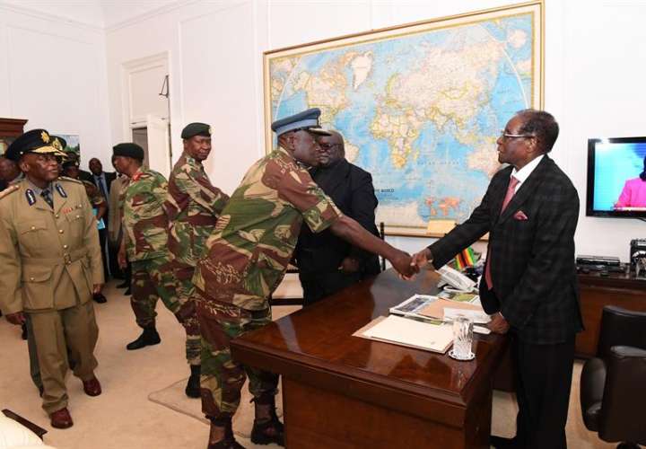 El presidente de Zimbabue, Robert Mugabe (d), saluda al comandante de las Fuerzas Aéreas del país, Perence Shiri (c), tras una reunión el domingo, con jefes militares y de seguridad en Harare. EFE/ The Herald FOTO CEDIDA/NO VENTAS