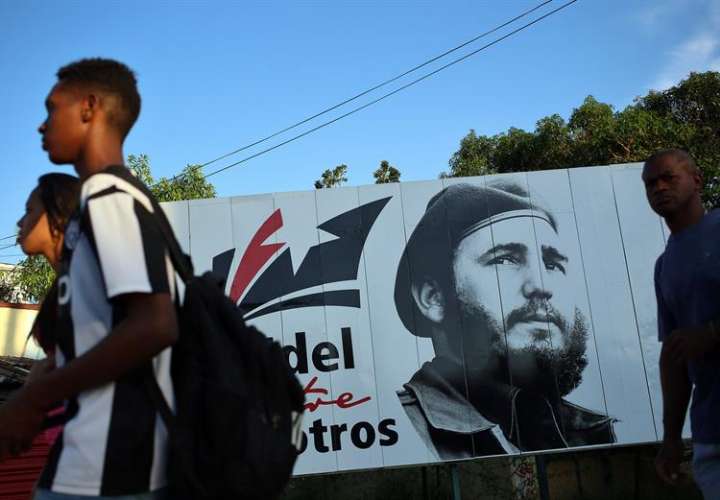 Varias personas caminan frente a un cartel con la imagen de Fidel Castro. / EFE