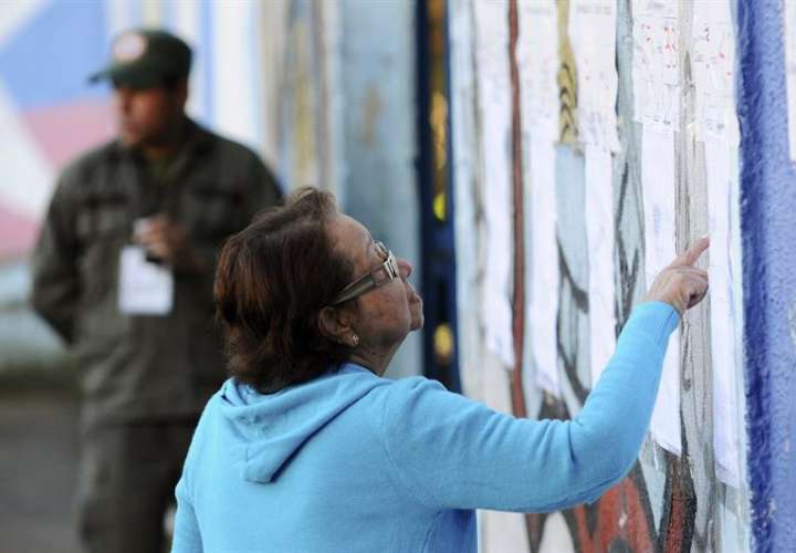 Una mujer busca su mesa de votación para participar de los comicios en Venezuela.  /  EFE