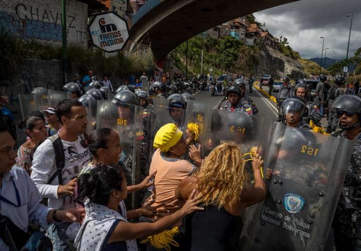 Un grupo de personas protesta frente a miembros de la Policía Nacional Bolivariana (PNB) hoy, jueves 28 de diciembre del 2017, en Caracas (Venezuela). EFE