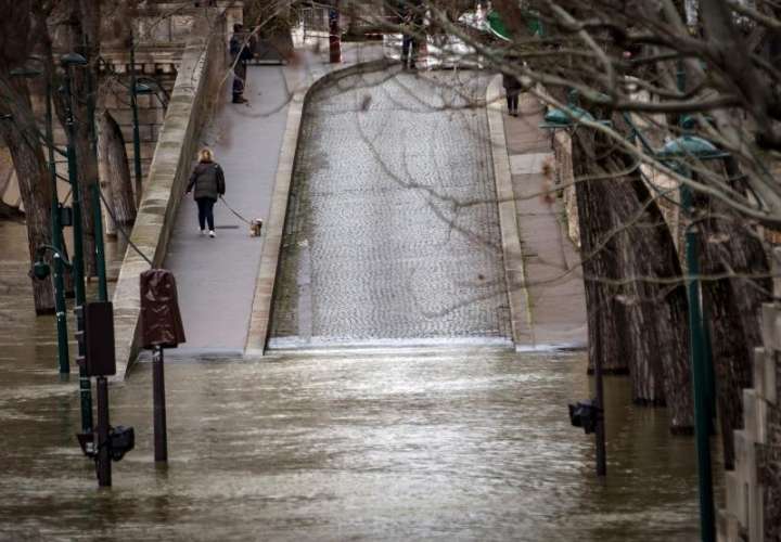 Una mujer pasea a su perro por una calle inundada a orillas del río Sena en París, Francia. EFE
