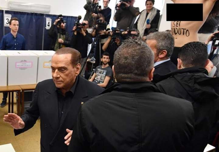 Exprimer ministro italiano y líder del partido &#039;Forza Italia&#039;, Silvio Berlusconi (izq.), Deja la mesa de votación cuando un activista &#039;Femen&#039; (R) presenta una protesta con el torso desnudo durante la votación en las elecciones generales. EFE