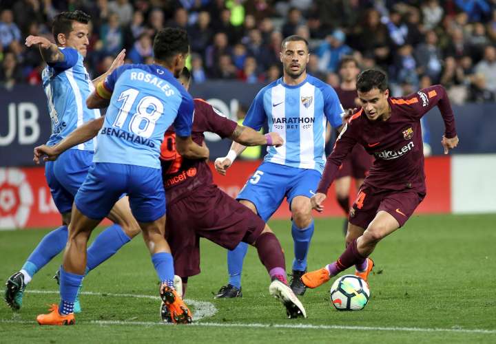 El delantero brasileño del Barcelona Philippe Coutinho (d) se lleva el balón ante varios rivales del Málaga. EFE/Daniel Pérez