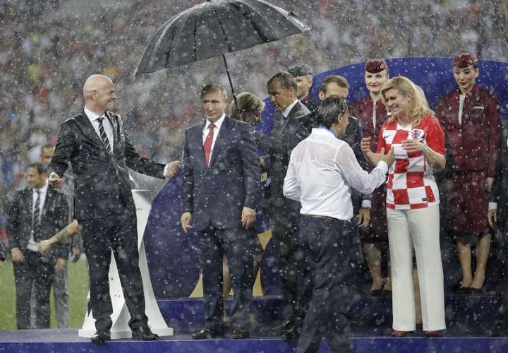 Gianni Infantino (izq.) comenzó a reírse a carcajadas al observar que el único que tenía paragua era Vladimir Putin. Foto AP