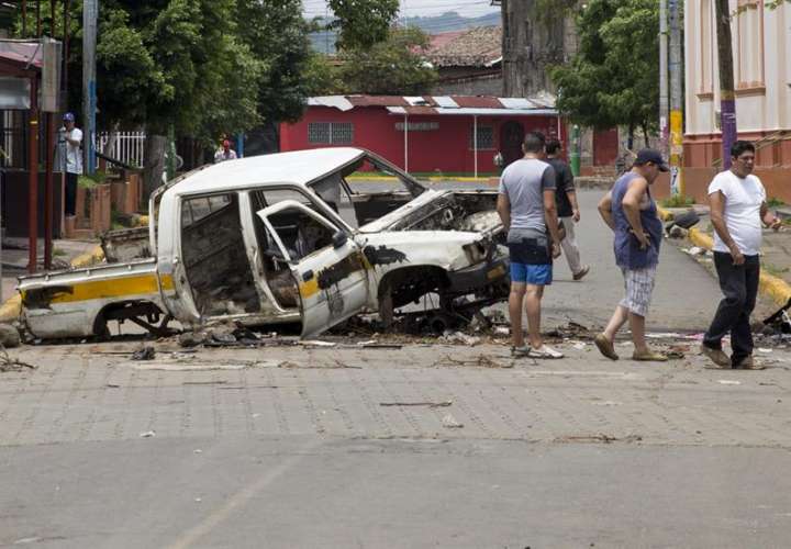 Ciudadanos pasan frente a un coche quemado, en la ciudad de Masaya (Nicaragua). EFE Archivo