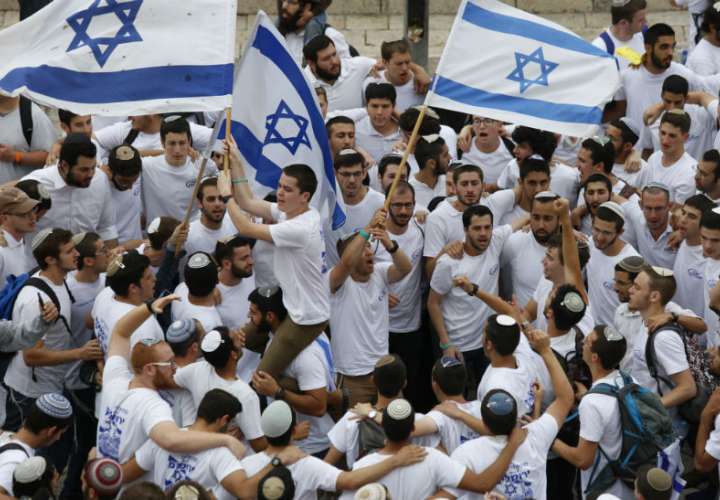 Jóvenes israelíes ondean banderas nacionales fuera de la Puerta de Damasco de la Ciudad Vieja, en Jerusalén. Foto: AP