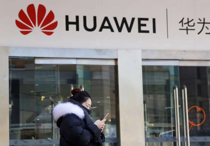 Una joven utiliza su teléfono móvil ante una tienda de la firma china Huawei en Pekín, China, EFE/Archivo