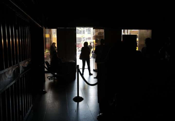 Un grupo de personas permanece en medio de la oscuridad al interior del edificio de la Asamblea Nacional este lunes en Caracas (Venezuela). EFE