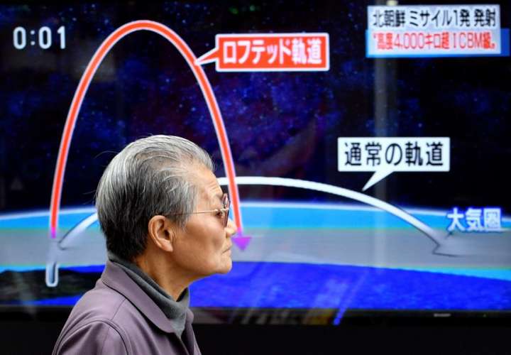Un ciudadano camina frente a un televisor que muestra los detalles del lanzamiento de un misil balístico de Corea del Norte. EFE