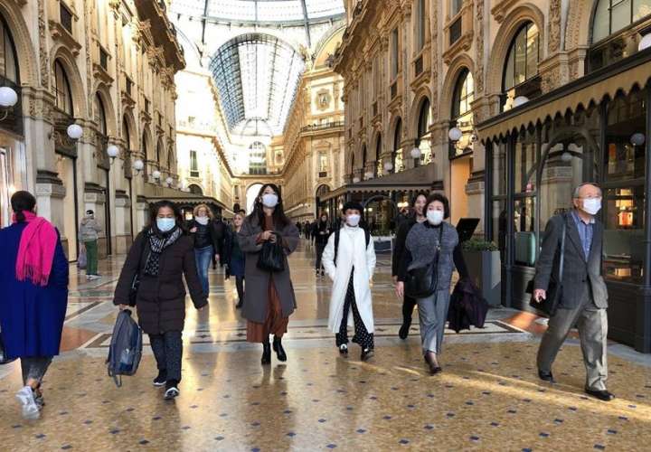 Las personas asiáticas con máscaras protectoras caminan en una Galleria Vittorio Emanuele inusualmente despoblada, en Milán, norte de Italia, el 24 de febrero de 2020.  EFE