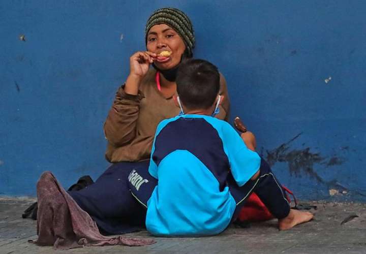 Una mujer y un niño permanecen sentados en una calle en la que piden diner este miércoles en Tegucigalpa (Honduras). EFE