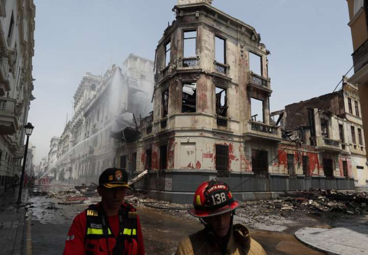 Bomberos trabajan en los alrededores de una casona que se incendió ayer durante la jornada de protestas, hoy, en Lima (Perú). EFE