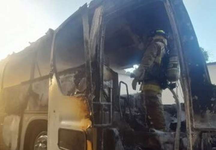 Bombero en labores de extinción dentro del bus incendiado.