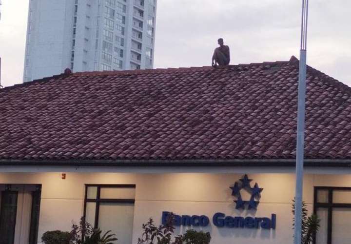 El hombre sentando en el techo de la entidad bancaria.