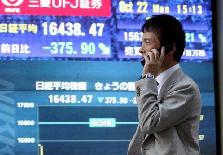 En la imagen de archivo, un hombre pasa delante de una pantalla que muestra el índice Nikkei de la Bolsa de Tokio. EFE