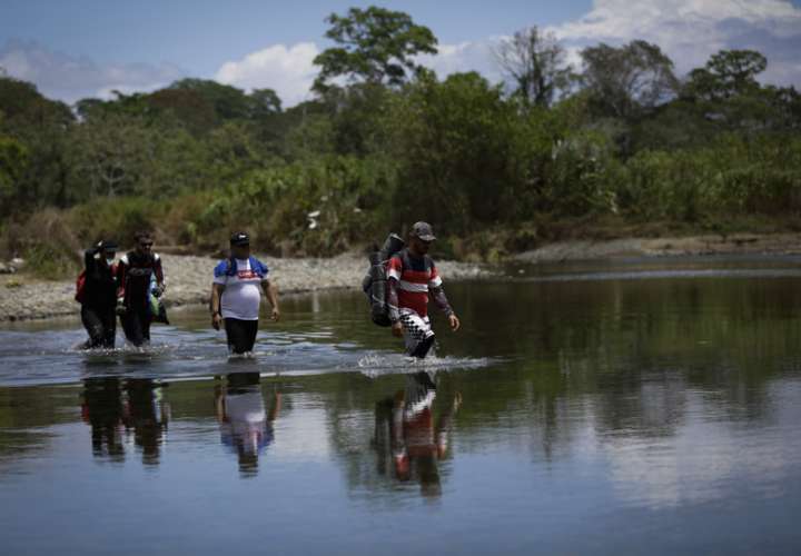 Personas migrantes cruzan el río Tuquesa, en Darién (Panamá), en una fotografía de archivo. EFE