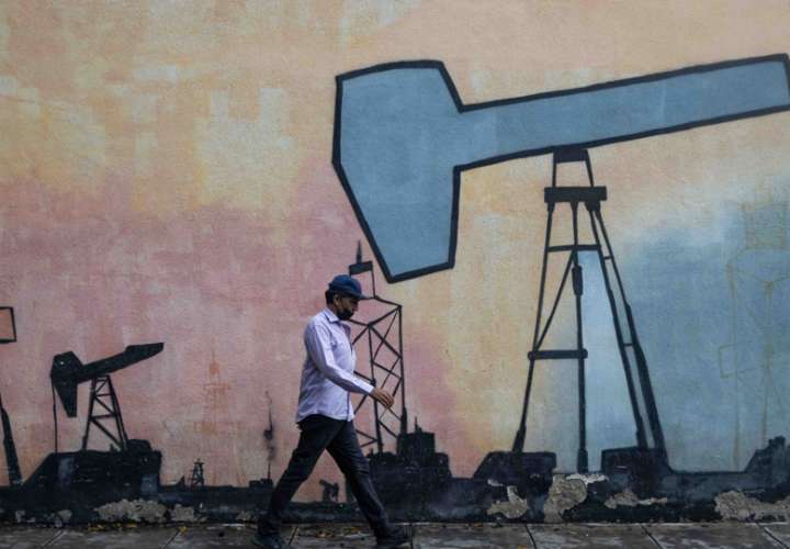 Un hombre pasa frente a un mural que muestra el proceso de extracción de petróleo frente a una sede de la estatal Petróleos de Venezuela S.A (Pdvsa). EFE