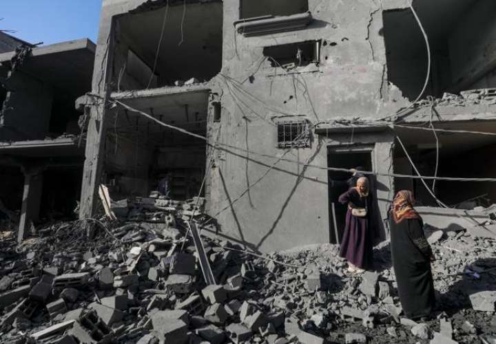 Mujeres palestinas inspeccionan su casa destruida tras los ataques aéreos israelíes en el campo de refugiados de Al Nusairat, Franja de Gaza. EFE / Archivo