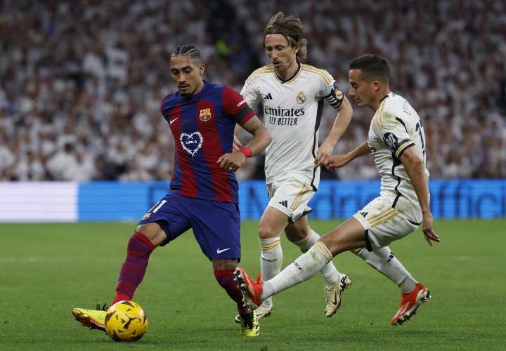 Lucas Vázquez (dcha) y Luka Modric (c) pelean por el balón con Raphinha./ EFE
