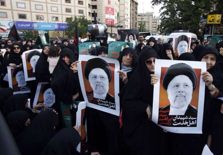 Mujeres iraníes sostienen carteles del presidente iraní Ebrahim Raisi durante una ceremonia de duelo en Teherán. EFE