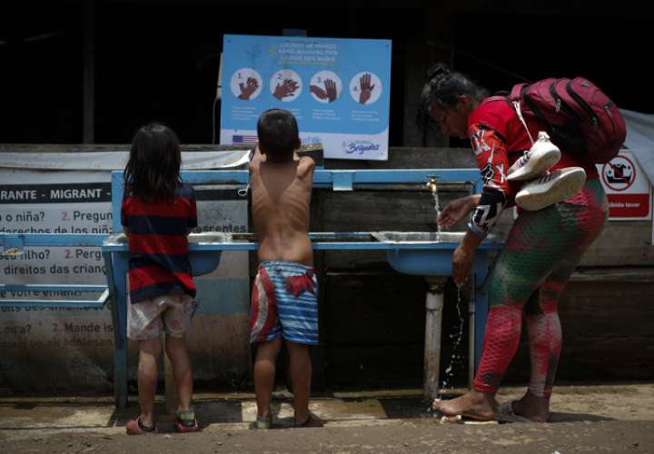 Mujer y dos niños migrantes tras cruzar la selva del Darién en Lajas Blancas. EFE / Archivo