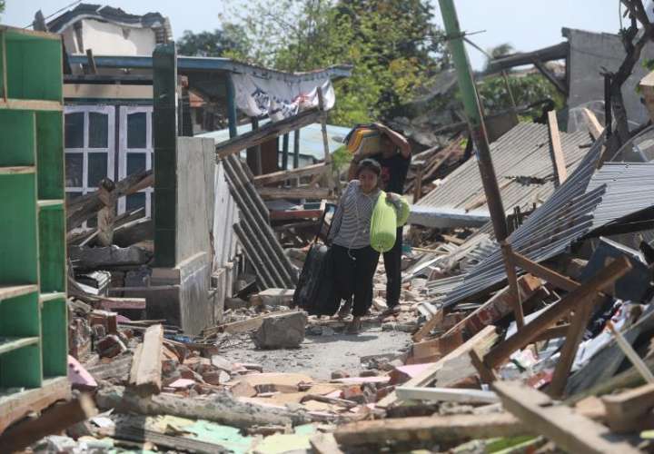 Residentes cargan con sus pertenencias entre los escombros tras los terremotos que desde el pasado domingo azotan el norte de la isla de Lombok (Indonesia). EFE