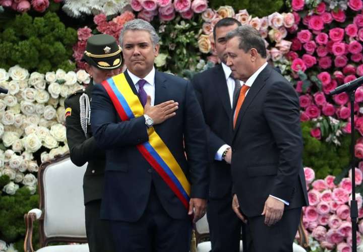 El presidente del Senado, Ernesto Macías (d), le impone la banda presidencial al nuevo presidente colombiano, Iván Duque Márquez (c-i), durante la ceremonia de investidura hoy, martes 7 de agosto de 2018, en la Plaza de Bolívar de Bogotá (Colombia). EFE
