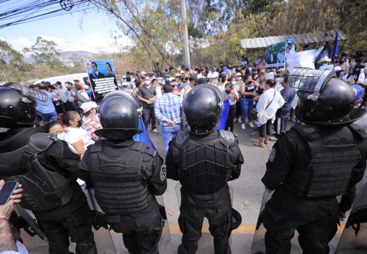 Miembros de la policía vigilan a simpatizantes del expresidente de Honduras Juan Orlando Hernández que se reúnen a las afueras de la Corte Suprema de Justicia. EFE