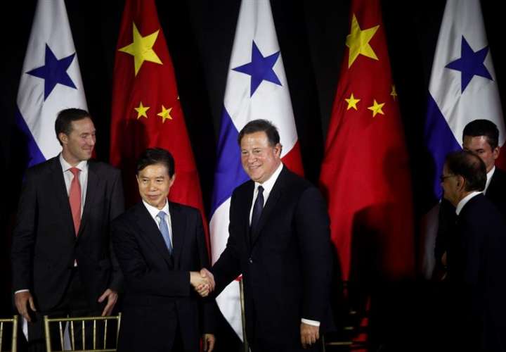 El ministro de Comercio de China, Zhong Shan (I), estrecha la mano al presidente de Panamá, Juan Carlos Varela (C), tras firmar un acuerdo de estudios de factibilidad para un sistema ferroviario y la suscripción de un TLC, el 7 de diciembre de 2017. EFE