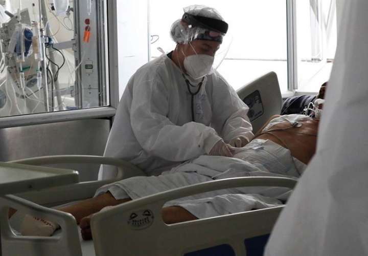 Una empleada de la salud atiende a un paciente en una unidad de cuidados intensivos para enfermos de covid-19. EFE