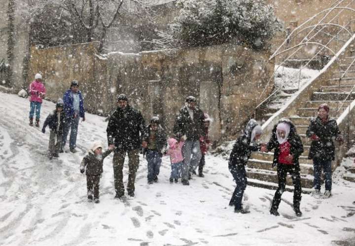 Adultos y niños caminaban bajo una intensa nevada caida hace unos años sobre Damasco. EFE/Archivo
