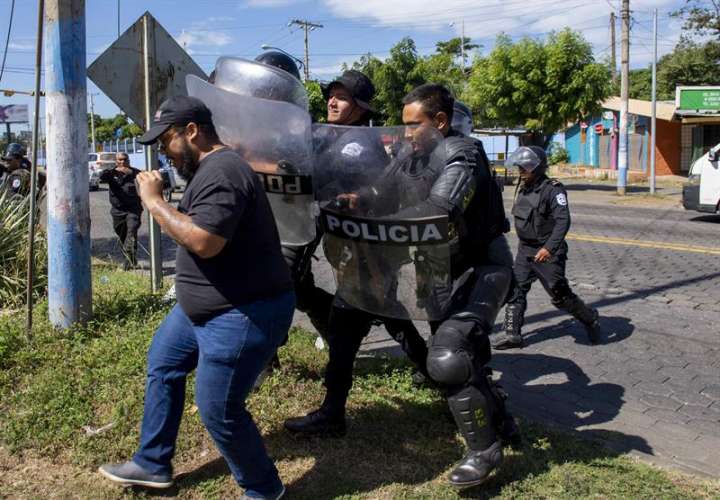 Agentes de la policía nacional repliegan al periodista Nestor Arce del semanario Confidencial al llegar a la sede central de la policía a pedir explicaciones sobre el allanamiento del medio de comunicación, ayer en Managua (Nicaragua). EFE