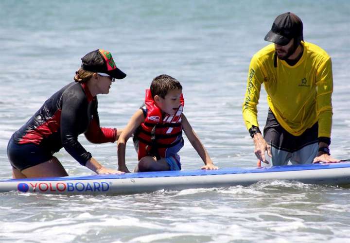 Un niño que padece autismo fue registrado al disfrutar de la brisa, las olas y la arena, durante una práctica terapéutica de surf en Ciudad de Panamá (Panamá). EFE