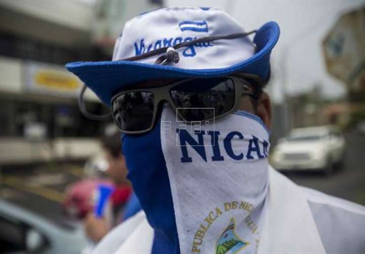 Un joven con la bandera de Nicaragua envuelta en la cara participa en un plantón frente a las instalaciones del Consejo Superior de la Empresa Privada (Cosep) en Managua (Nicaragua). EFE