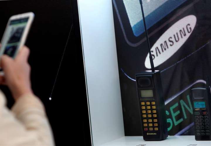 Un visitante toma imágenes de dos teléfonos de Samsung, el SH-100 de 1988 (i) y el SH-770 de 1994 (d) que están expuestos en el expositor de la firma corean durante la XIX edición del Mobile World Congress (MWC). EFE/Archivo