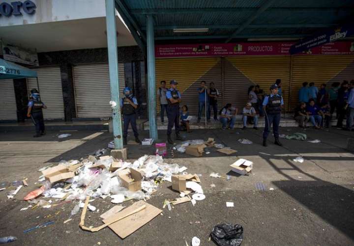 Comerciantes y miembros de la Policía Nacional fueron registrados este viernes al vigilar varios negocios después de un intento de saqueo en el Mercado Oriental, en Managua (Nicaragua). EFE